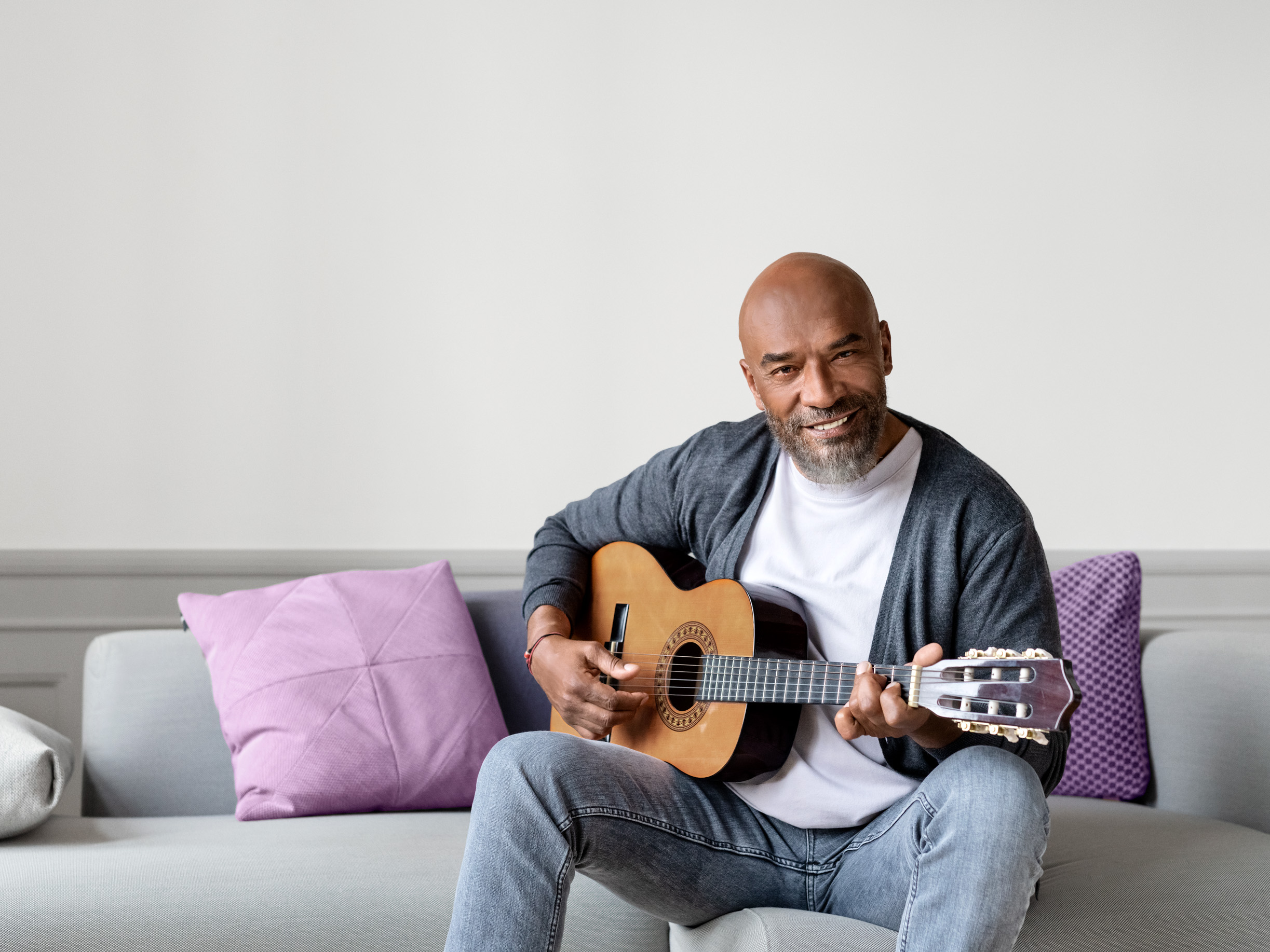 Man sitting in a sofa playing guitar