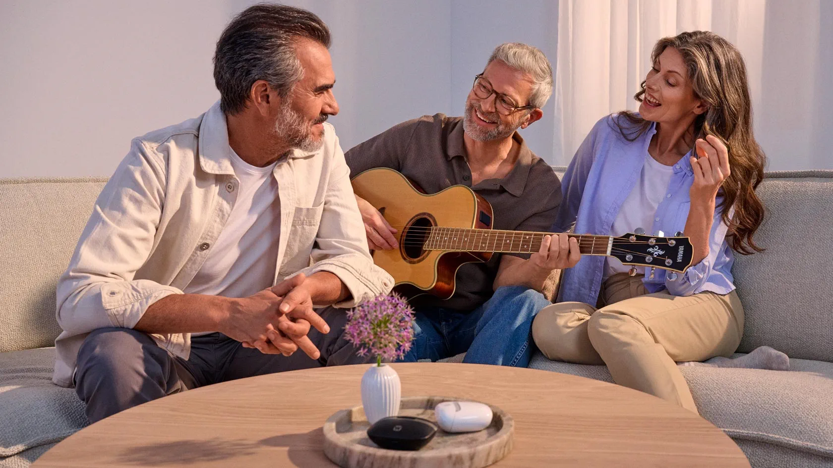 Casual gathering of friends around a guitar, wearing hearing aids.