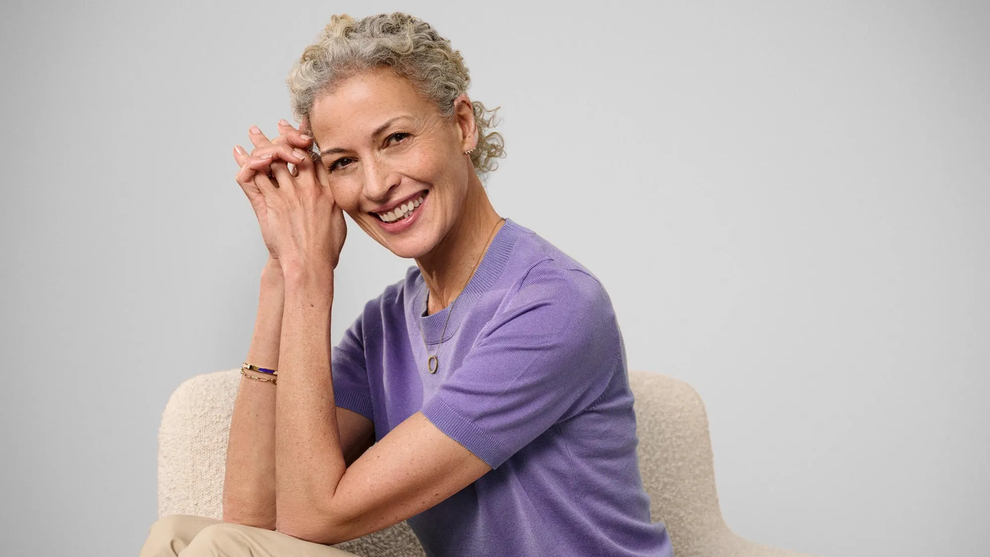 Happy woman sitting, showcasing hearing aids.