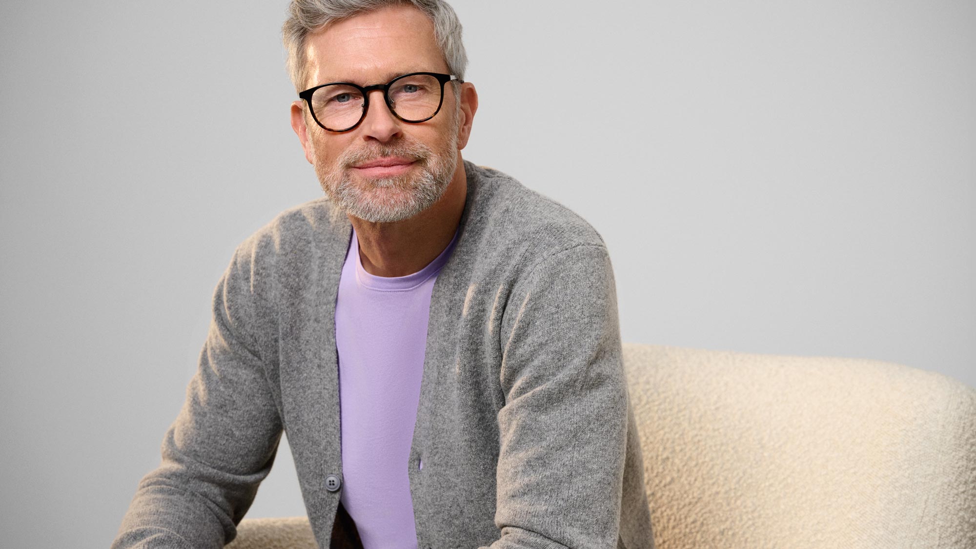 Man with glasses staring, indicating hearing improvement.
