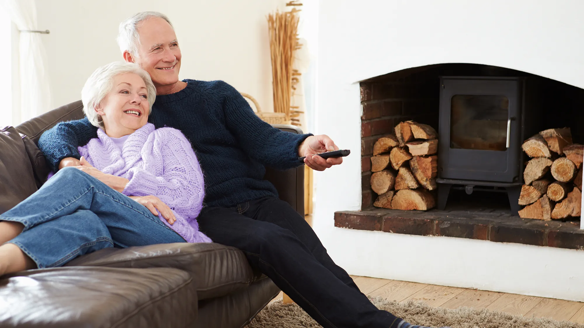Elderly couple having a casual time watching tv wearing hearing aids
