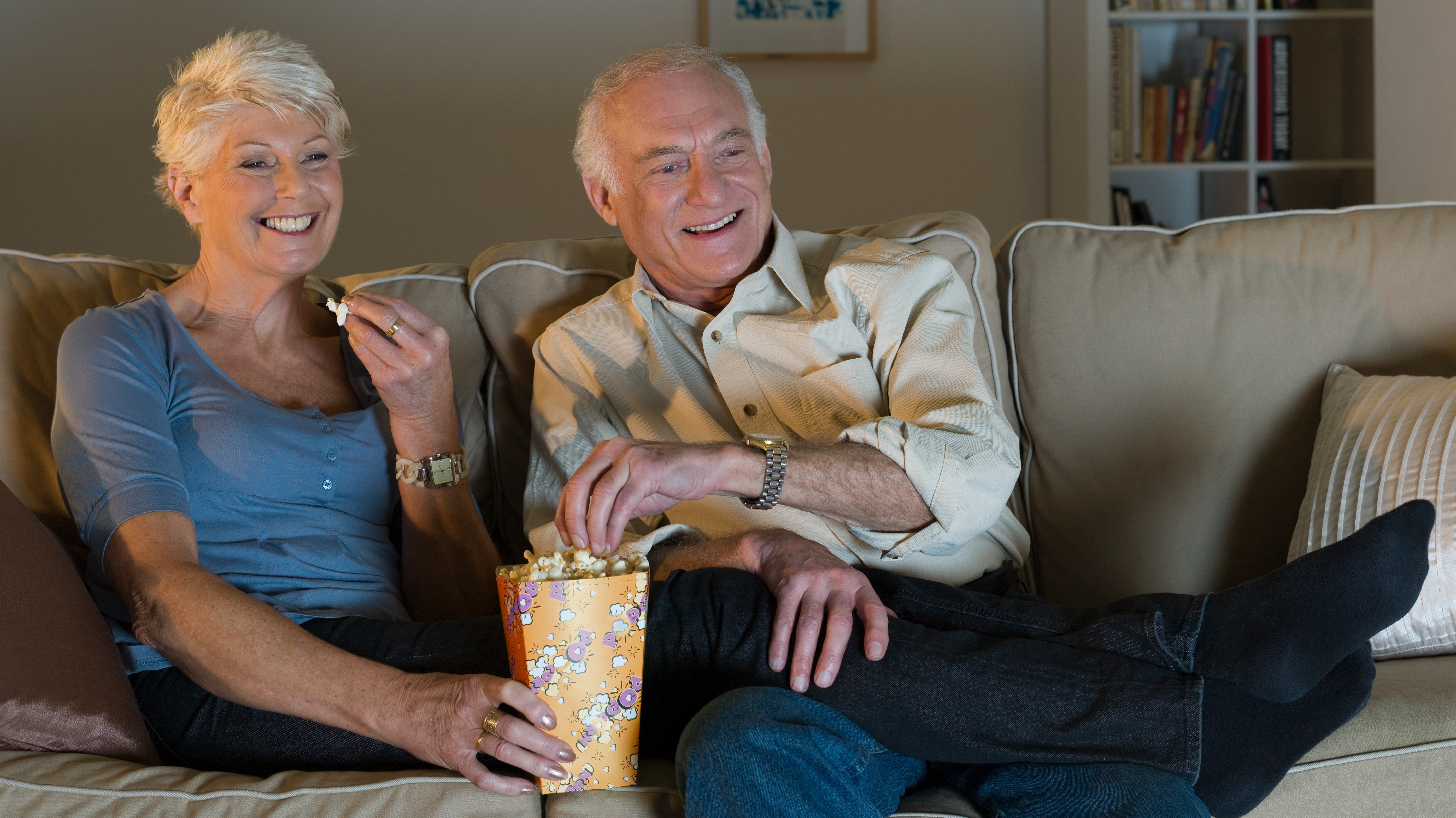 A senior couple watching tv and enjoying each others company wearing hearing aids