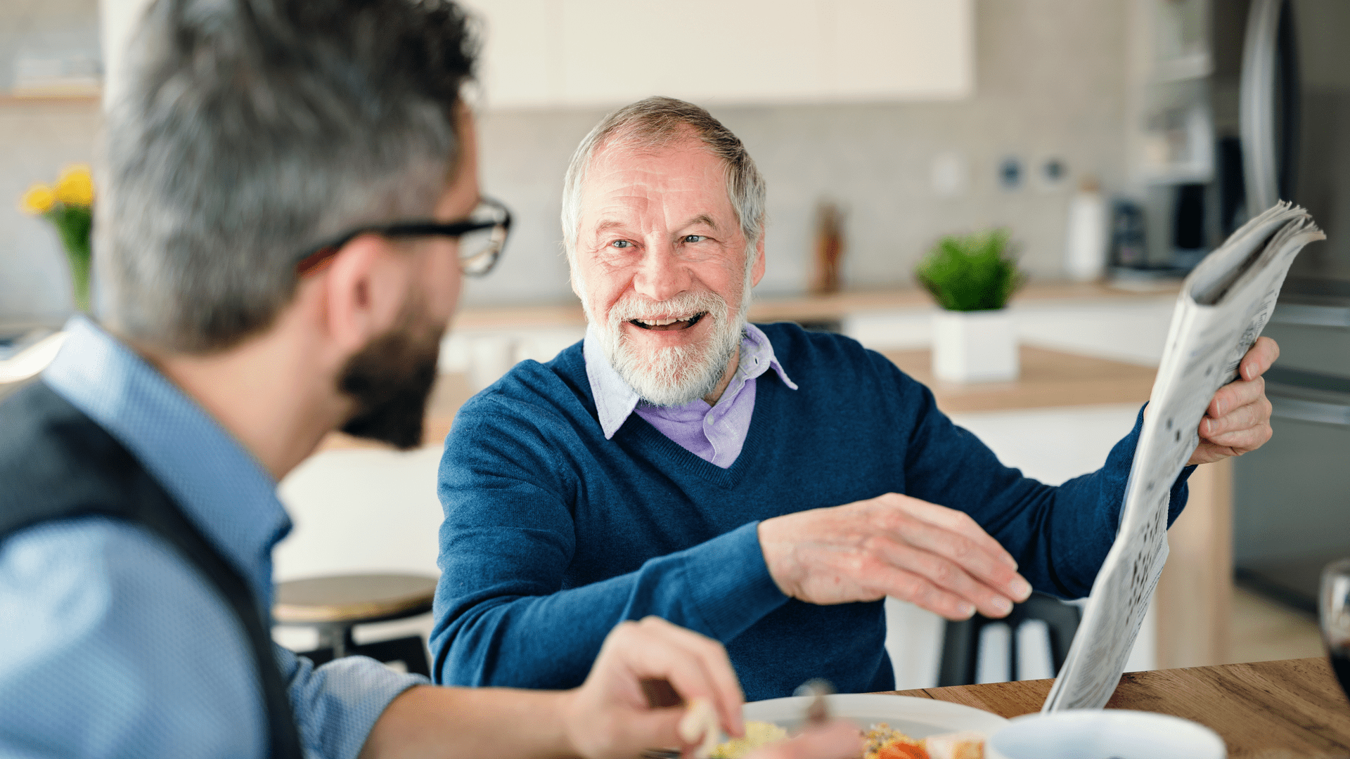 Man talking to elderly during lunch with hearing aids