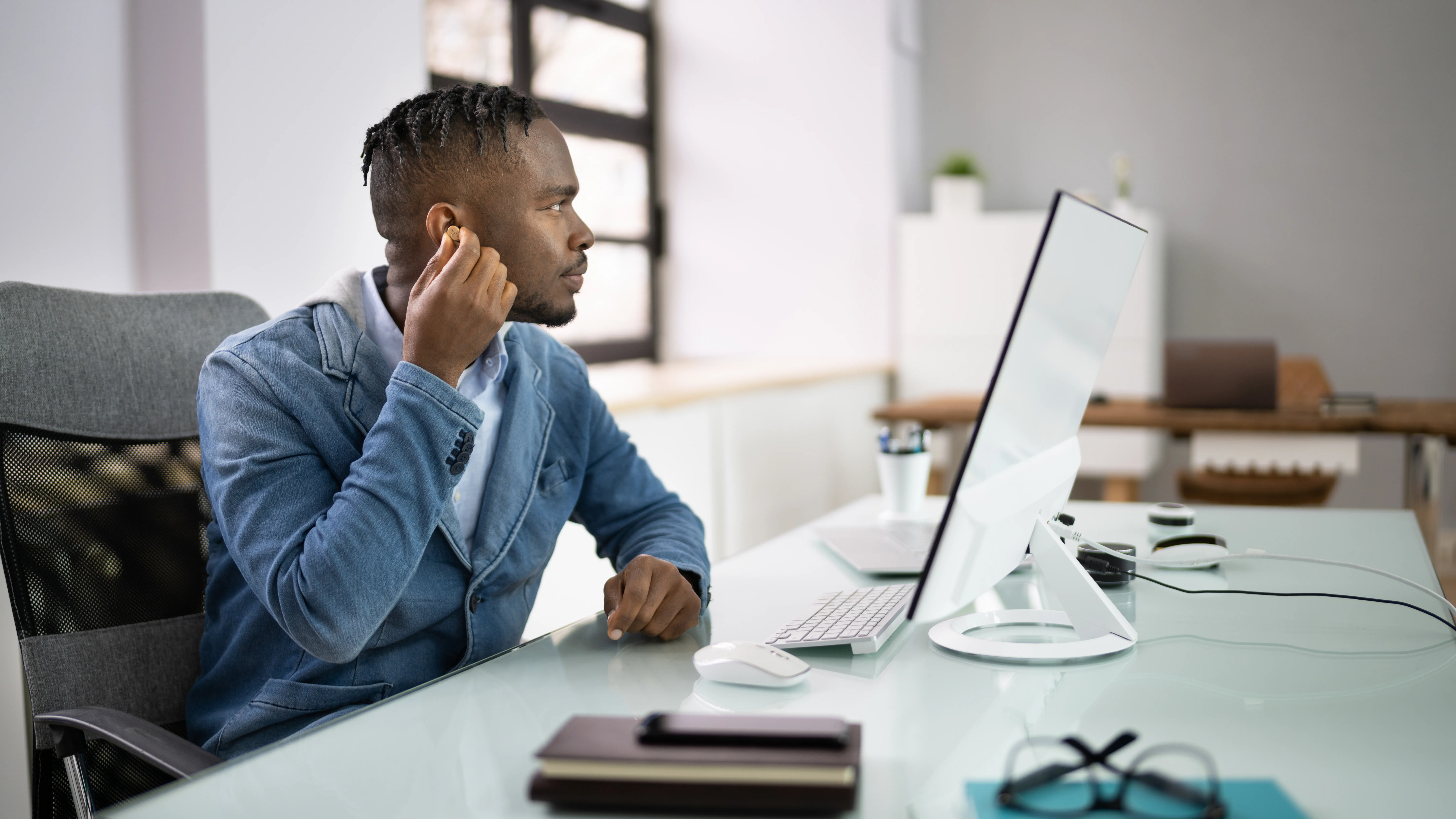 Man adjusting his hearing aids in the office