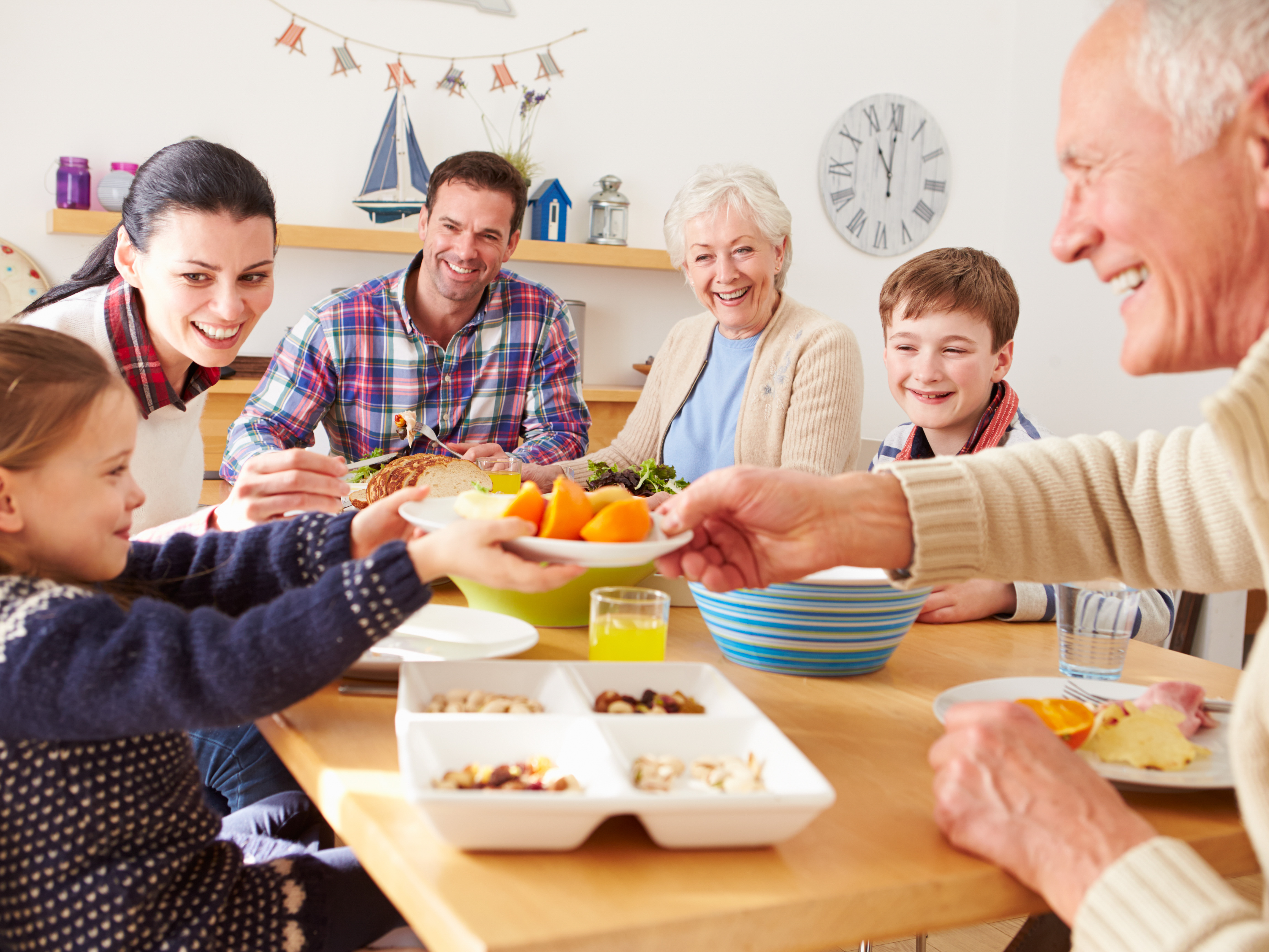 Multi generation family eating lunch at kitchen table using hearing aids