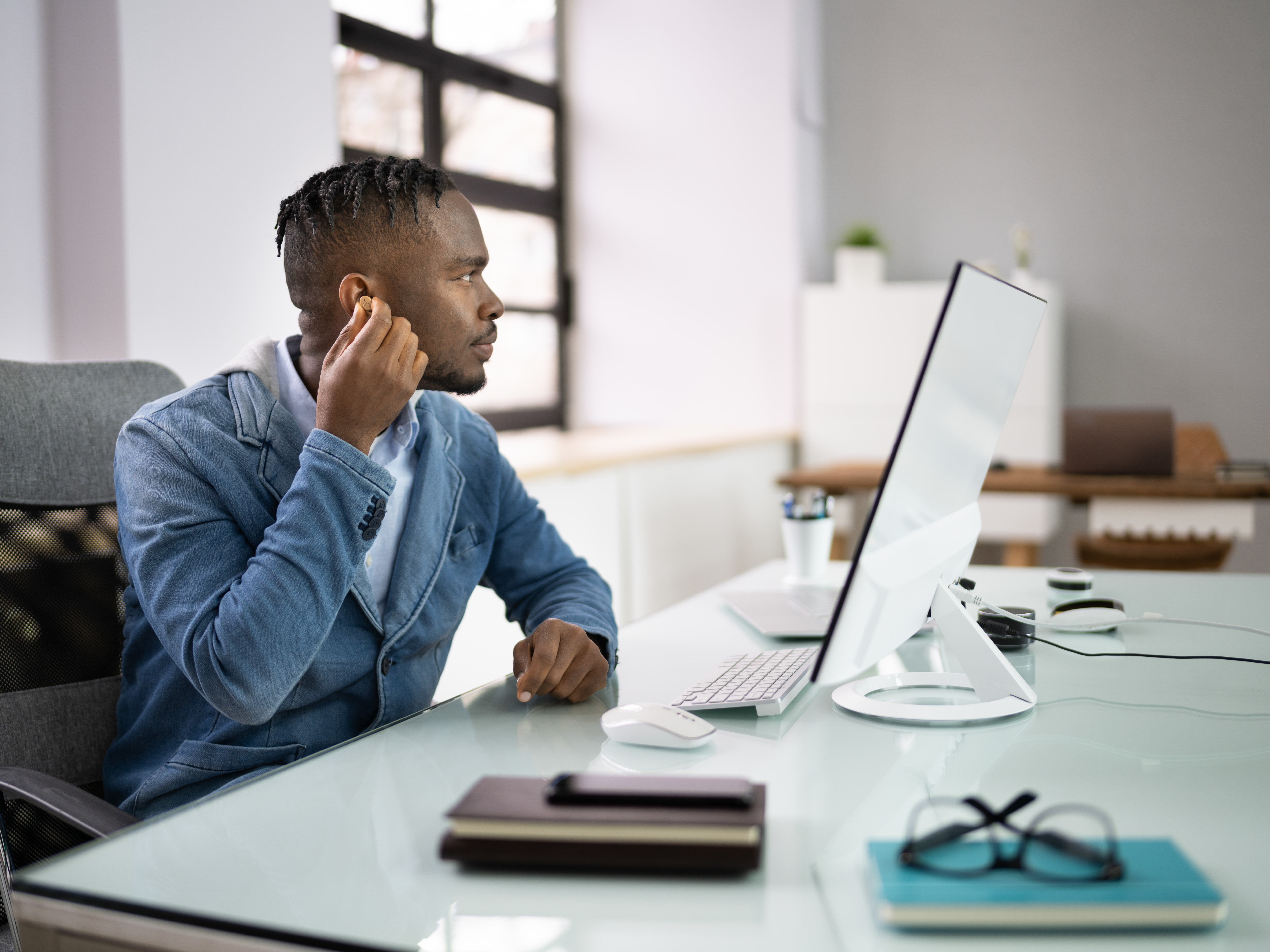 Man adjusting his hearing aids in the office