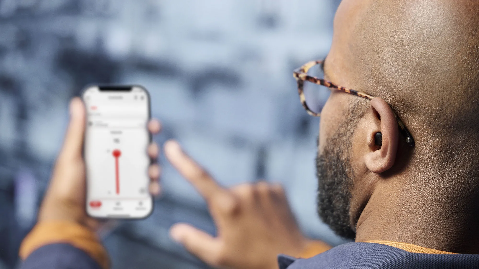 Man wearing Signia Insio Charge&Go CIC IX hearing aids whileadjusting sound from smart phone app