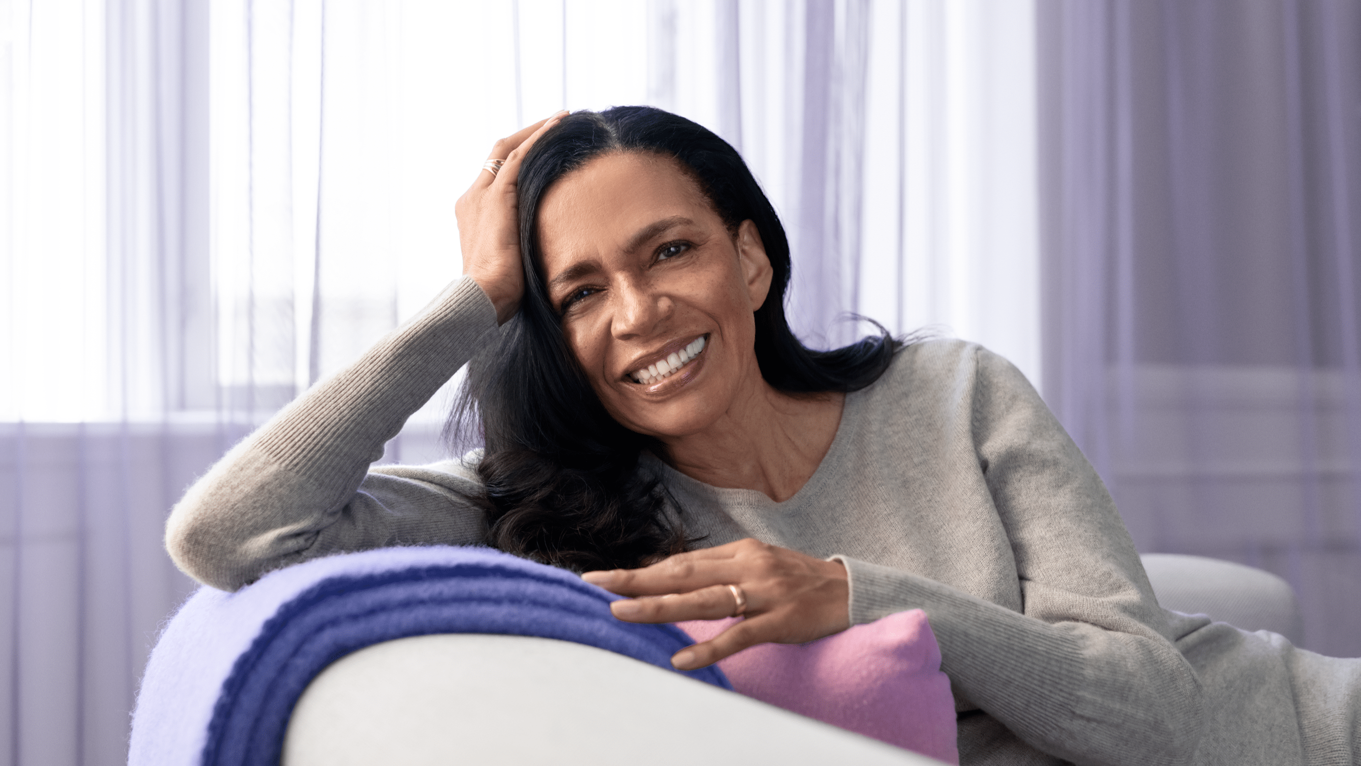 The woman is happily relying on the sofa and enjoying the sound.