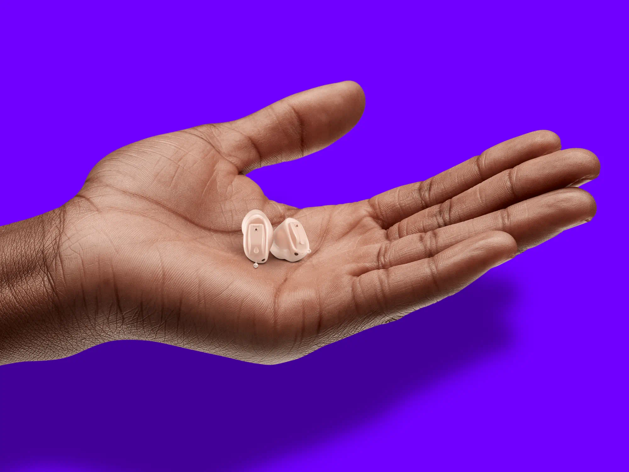 A hand is presenting the new hearing aids from WSA.
