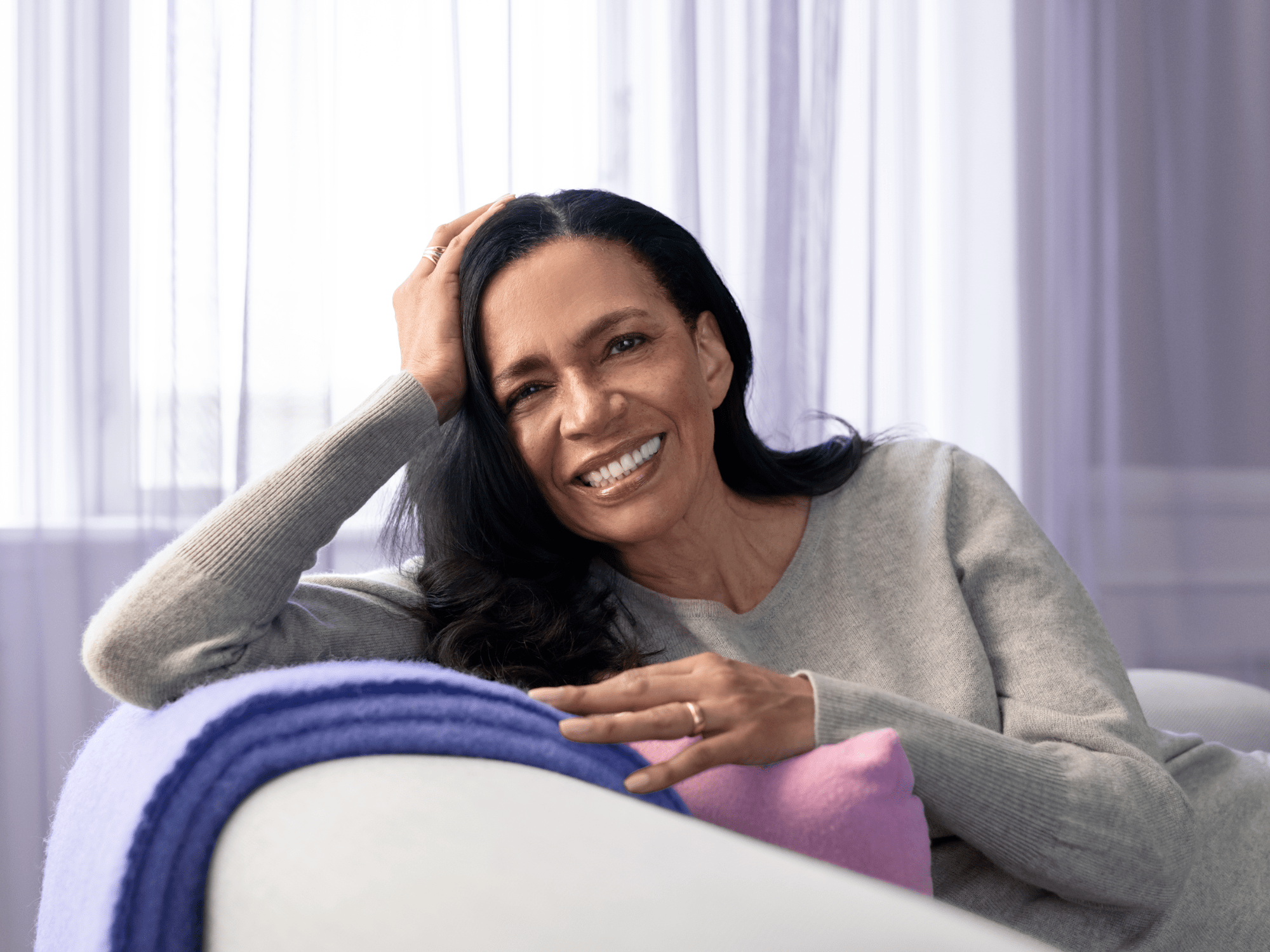 The woman is happily relying on the sofa and enjoying the sound.