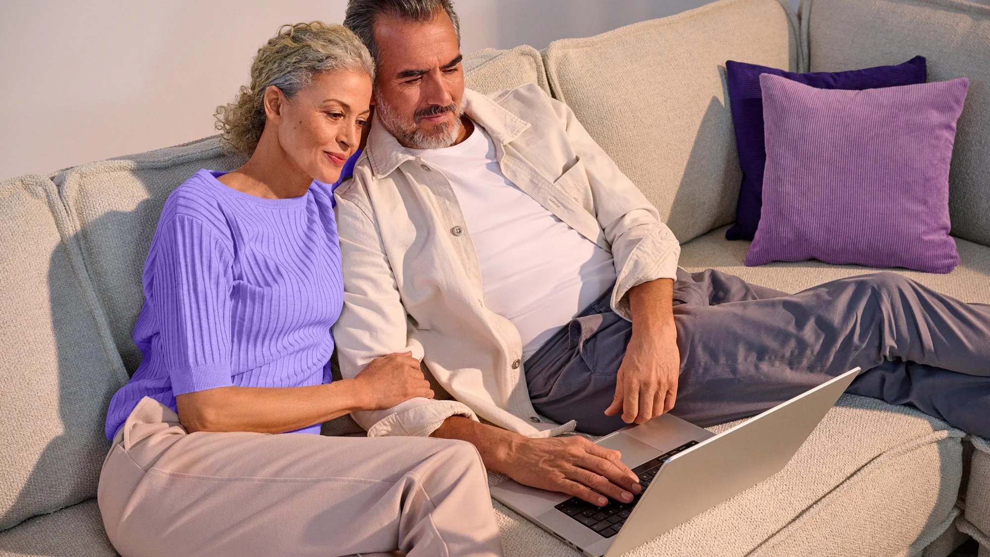 couple at home on laptop, wearing hearing aids
