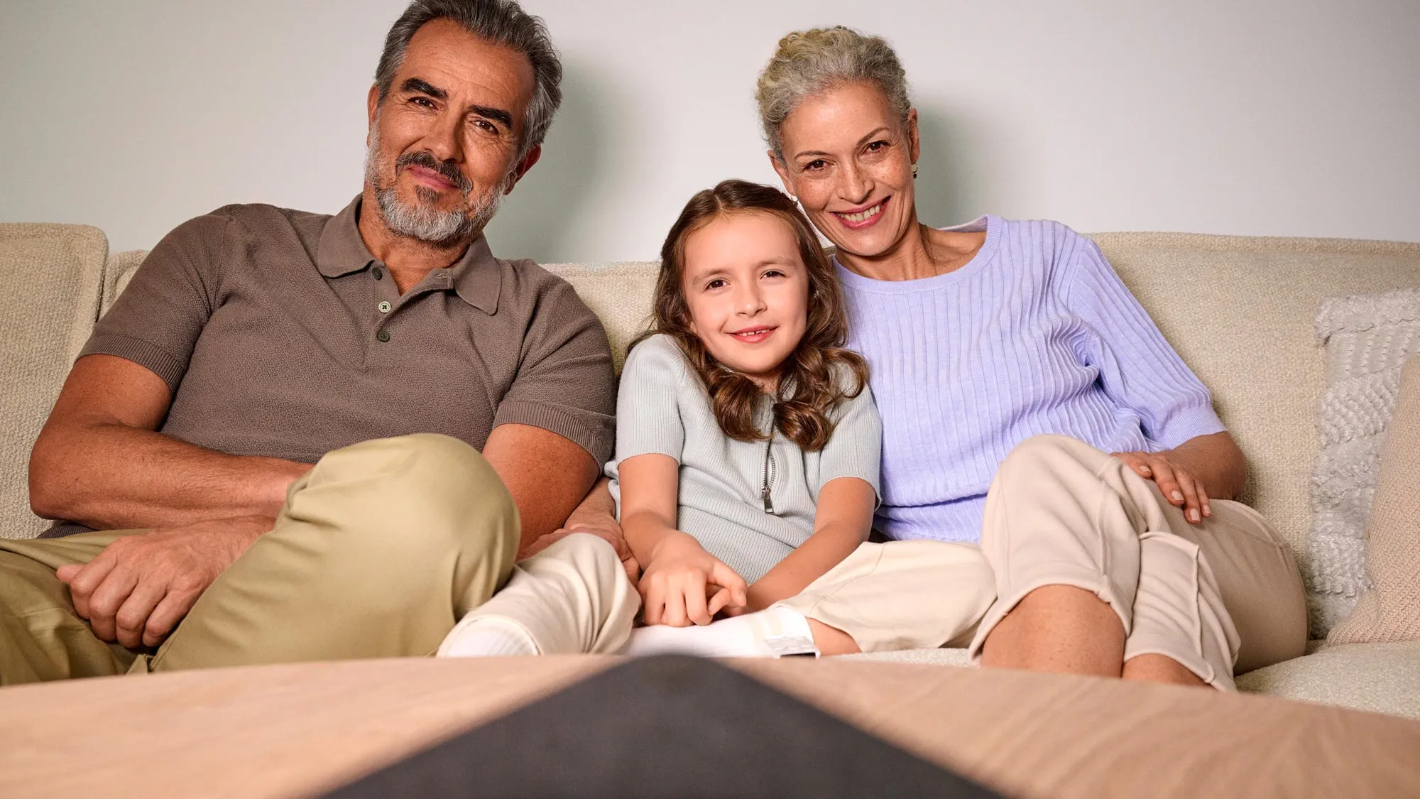 A family is at home on the sofa, with one member wearing hearing aids