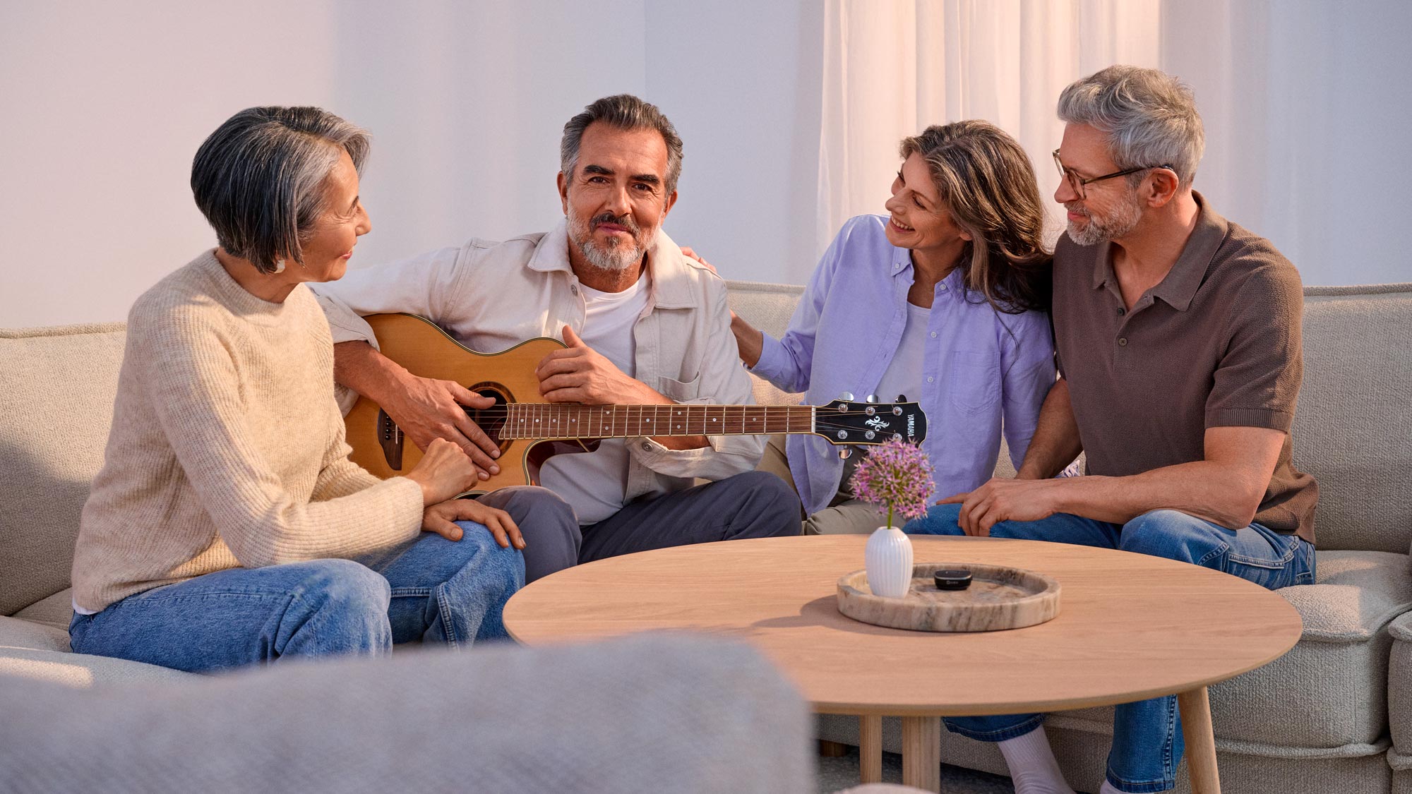 Friends having fun, playing the guitar, wearing CROS hearing aids
