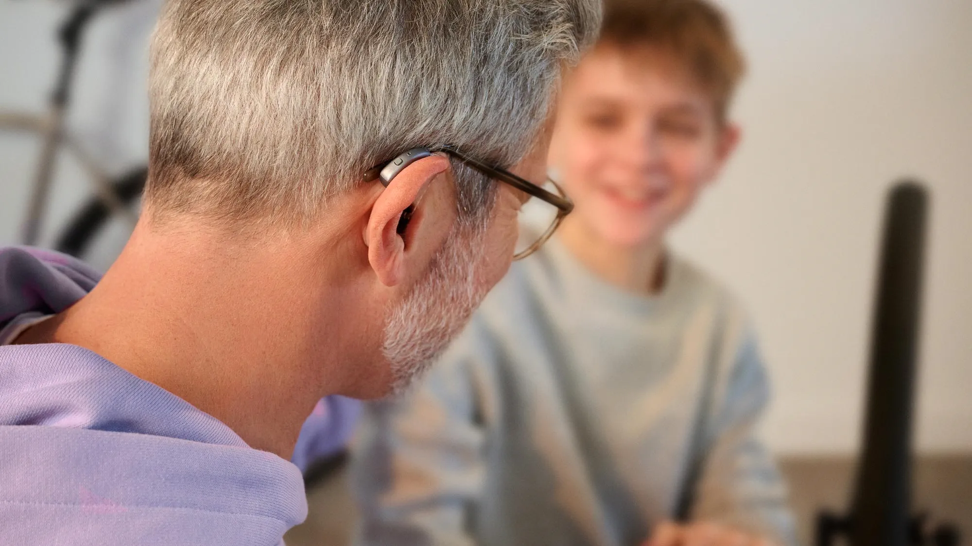 A man wearing hearing aids is having a conversation with his grandson