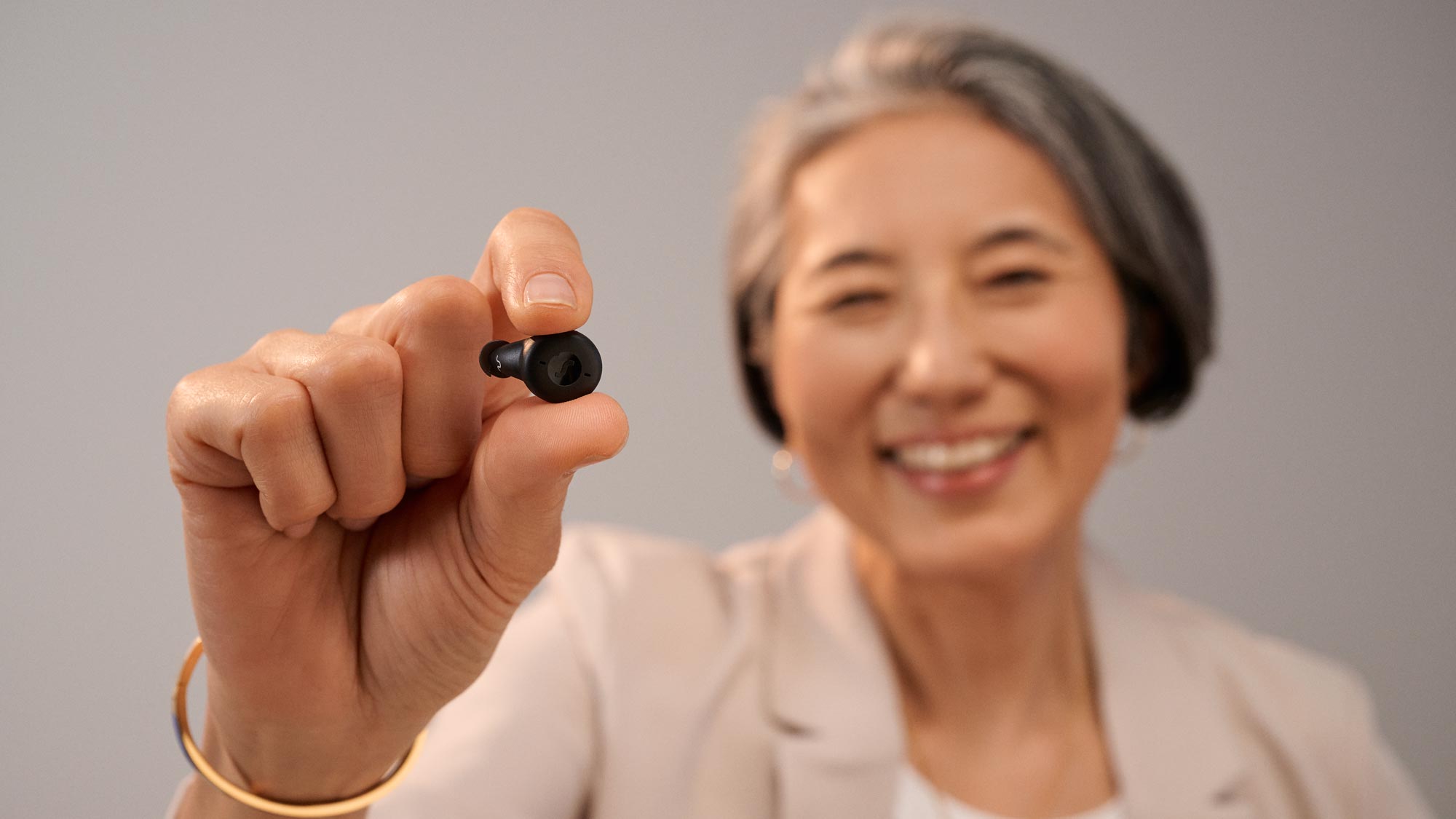 woman smiling, holding hearing aids