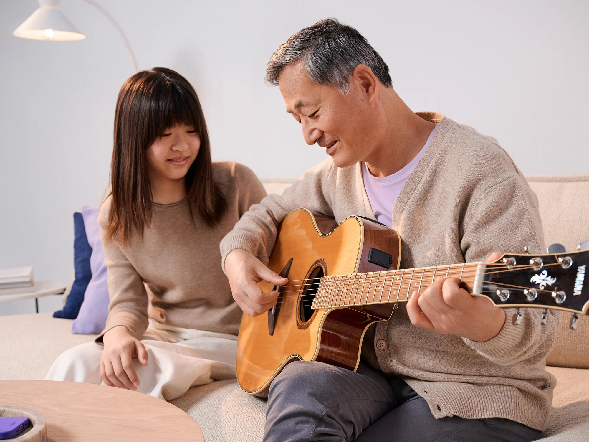 Father and daughter playing guitar wearing hearing aids