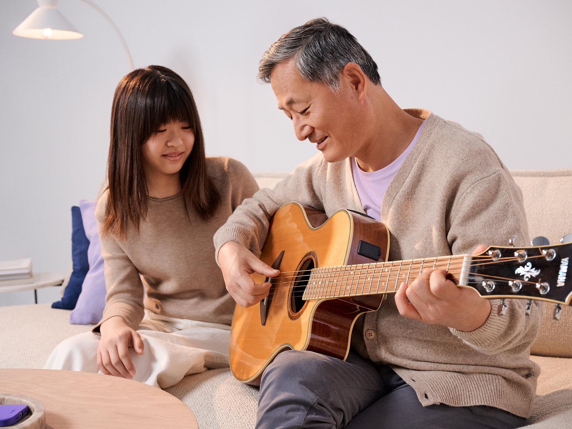 Father and daughter playing guitar wearing hearing aids