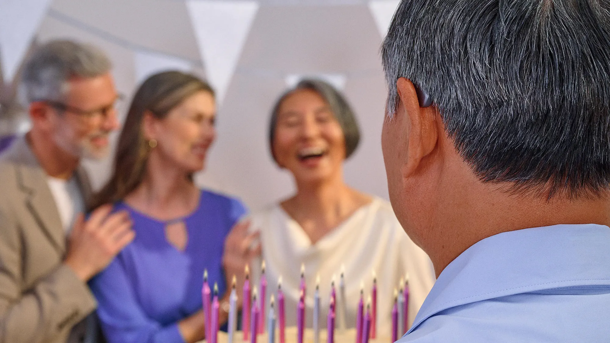 Group of friends celebrating a birthday, some wearing hearing aids.