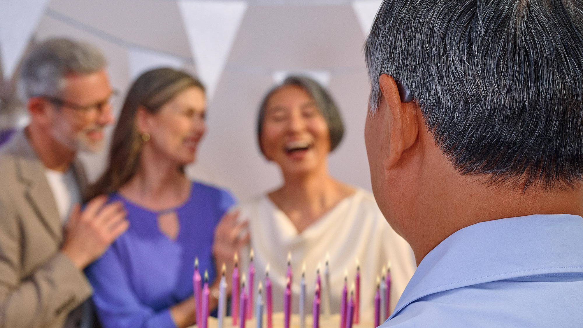Group of friends celebrating a birthday, some wearing hearing aids.