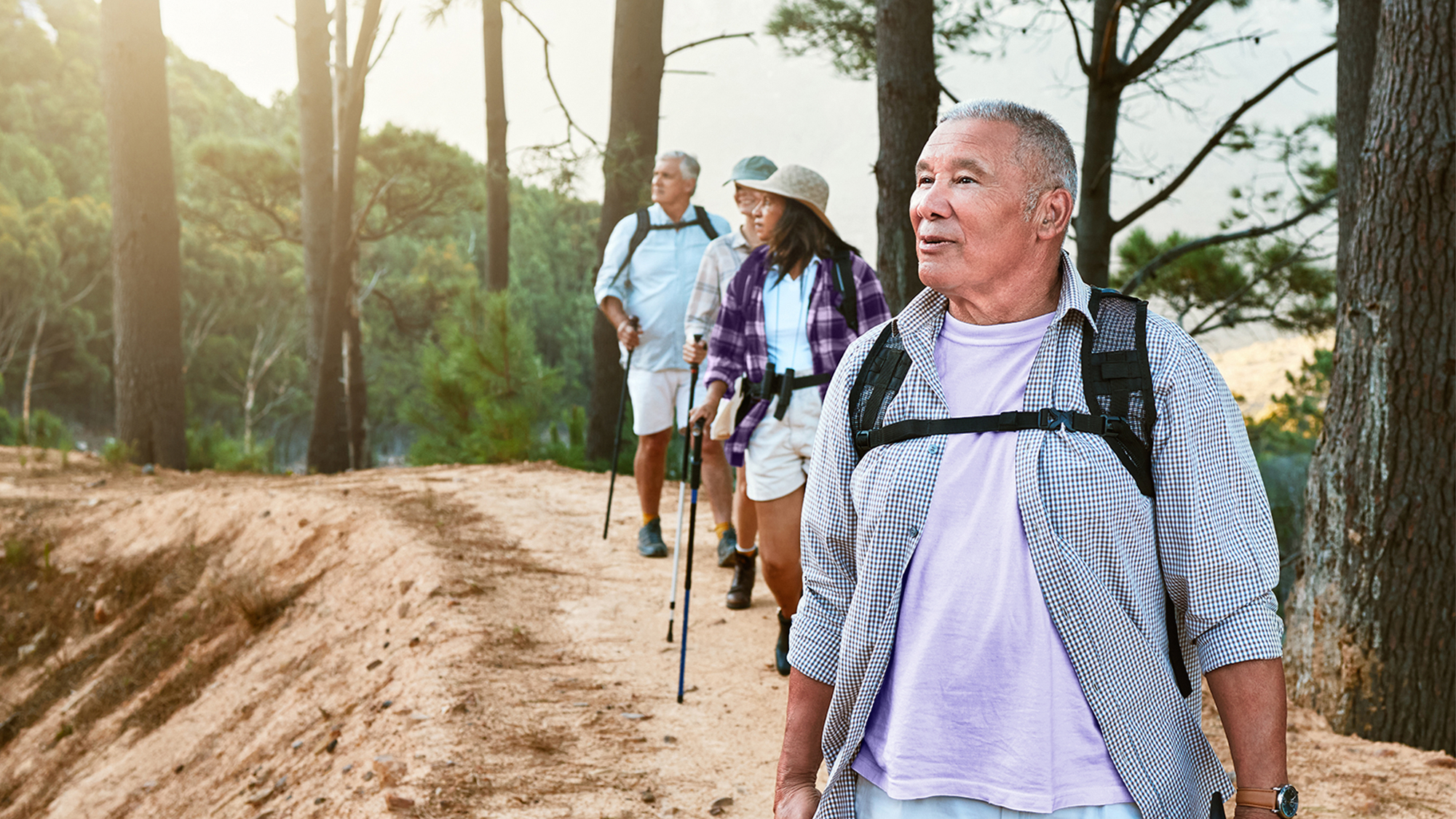 Group of friends hiking outdoors, using hearing aids for better communication.
