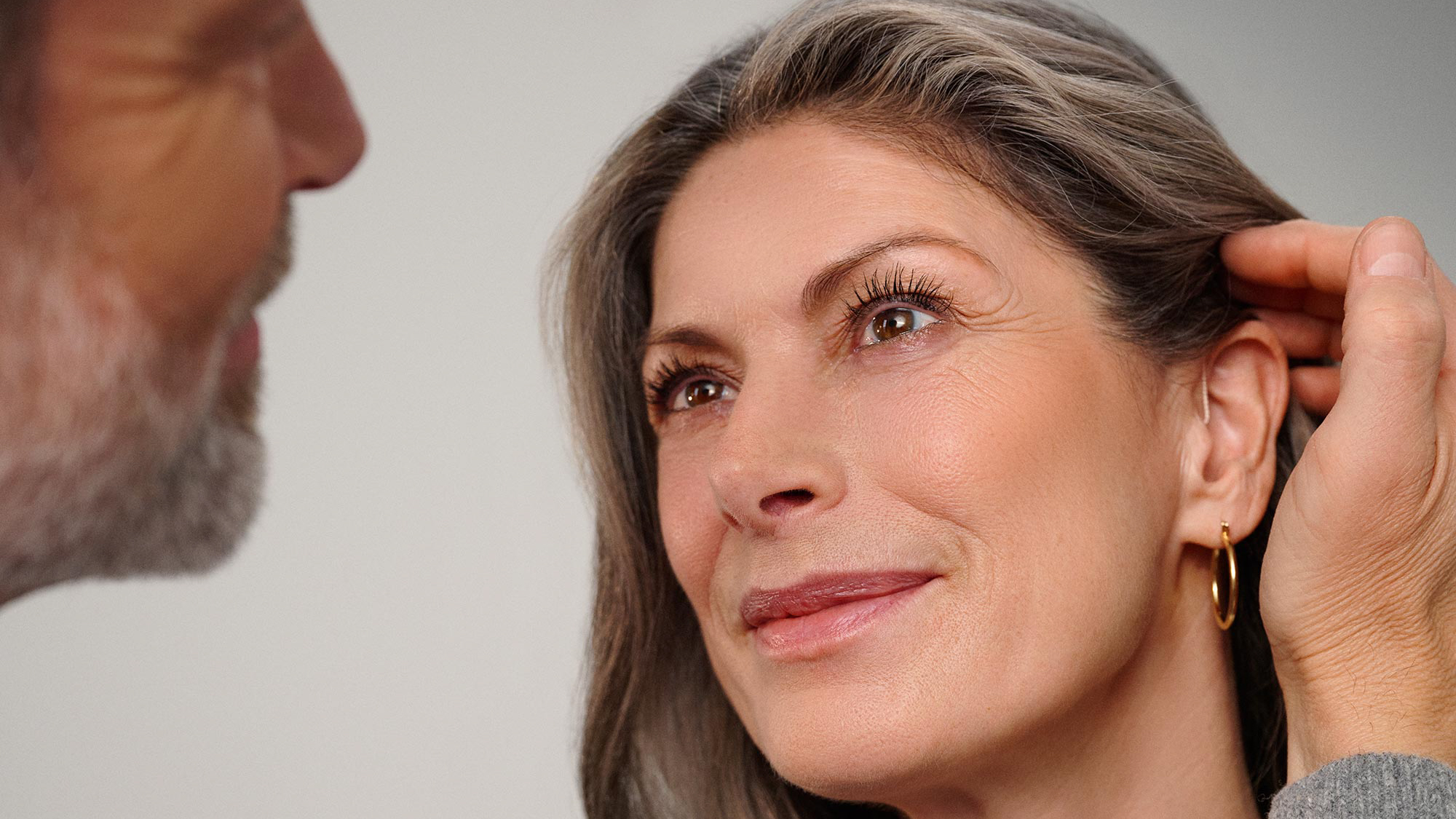 Couple sharing an affectionate moment, with hearing aids visible.