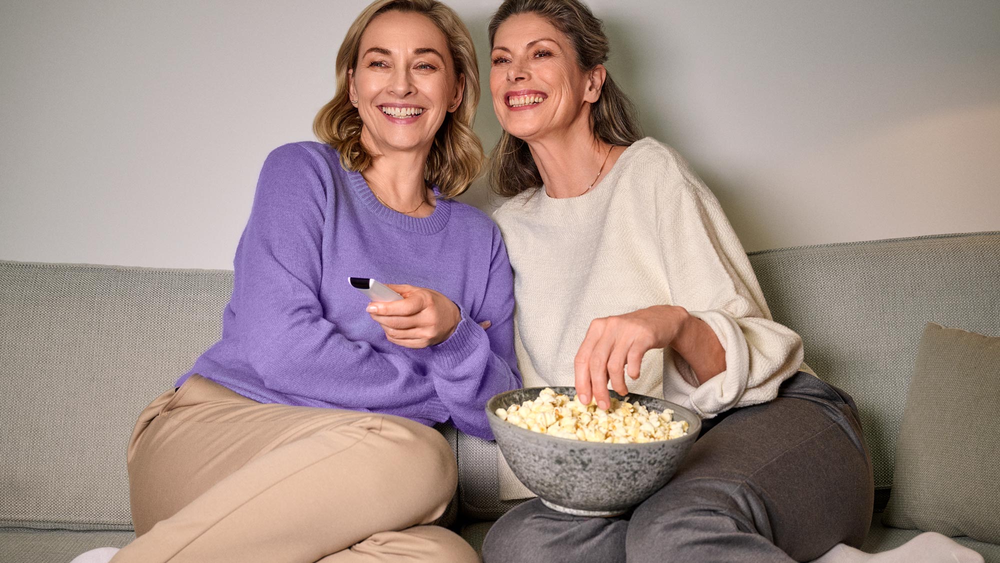 Friends eating popcorn and watching tv wearing hearing aids 