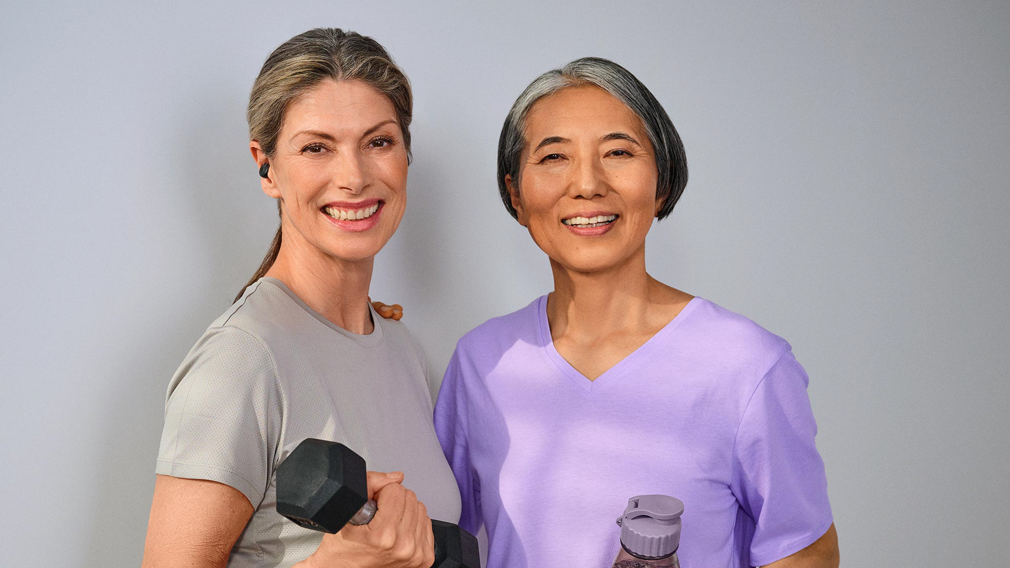 Women friends working out together, wearing hearing aids for clear interactions.