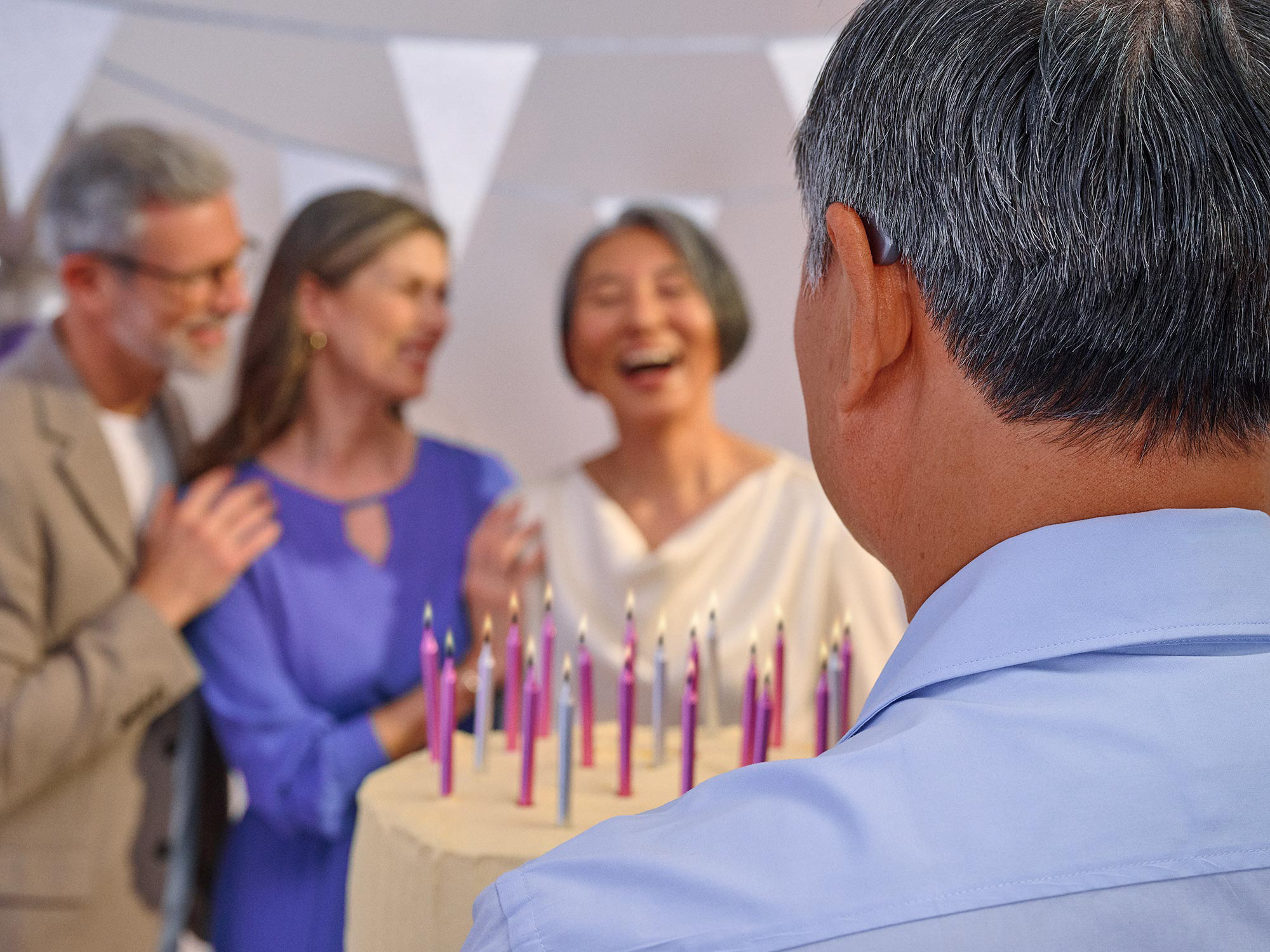 Group of friends celebrating a birthday, some wearing hearing aids.