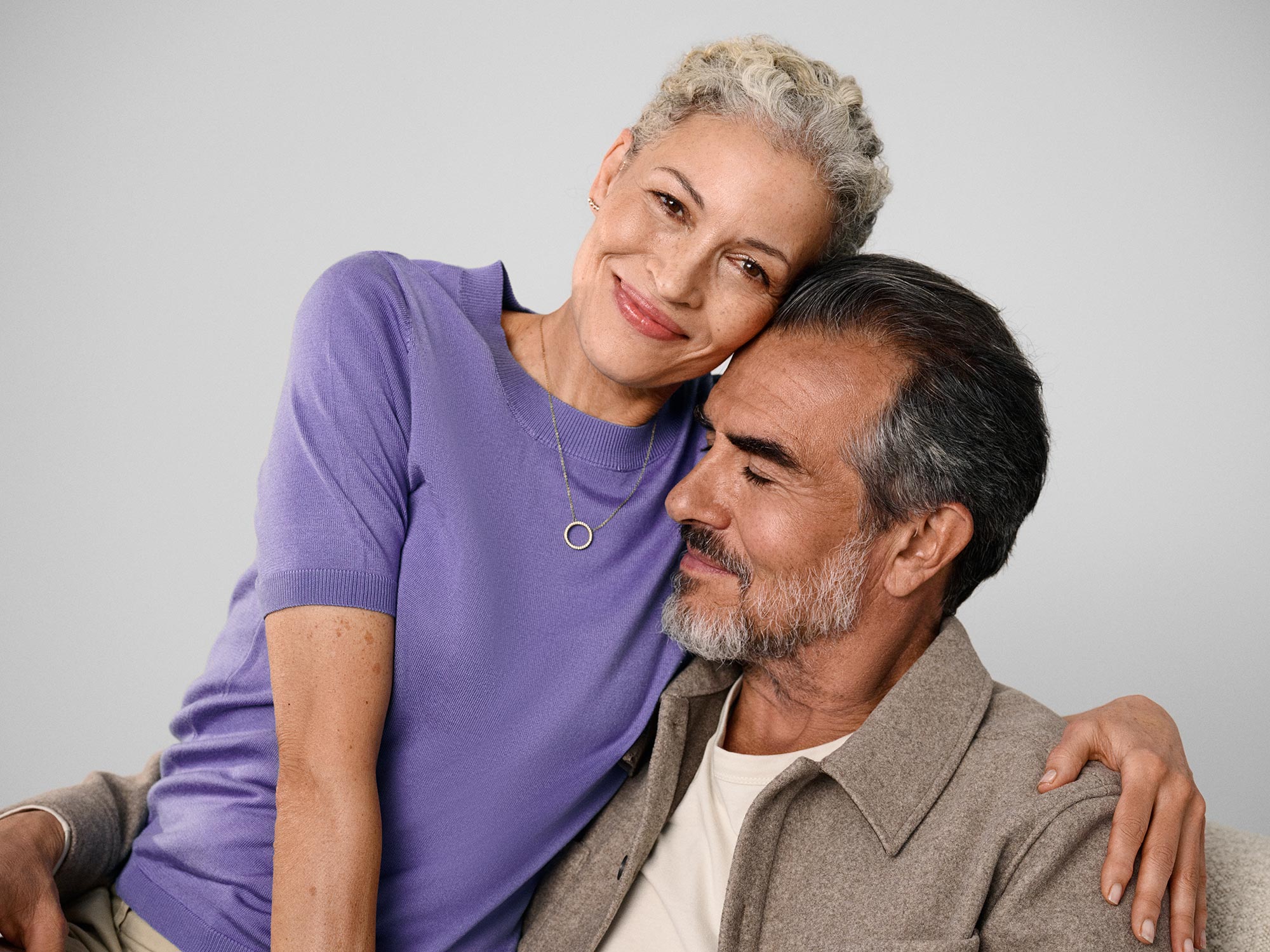 A couple smiling, both wearing hearing aids