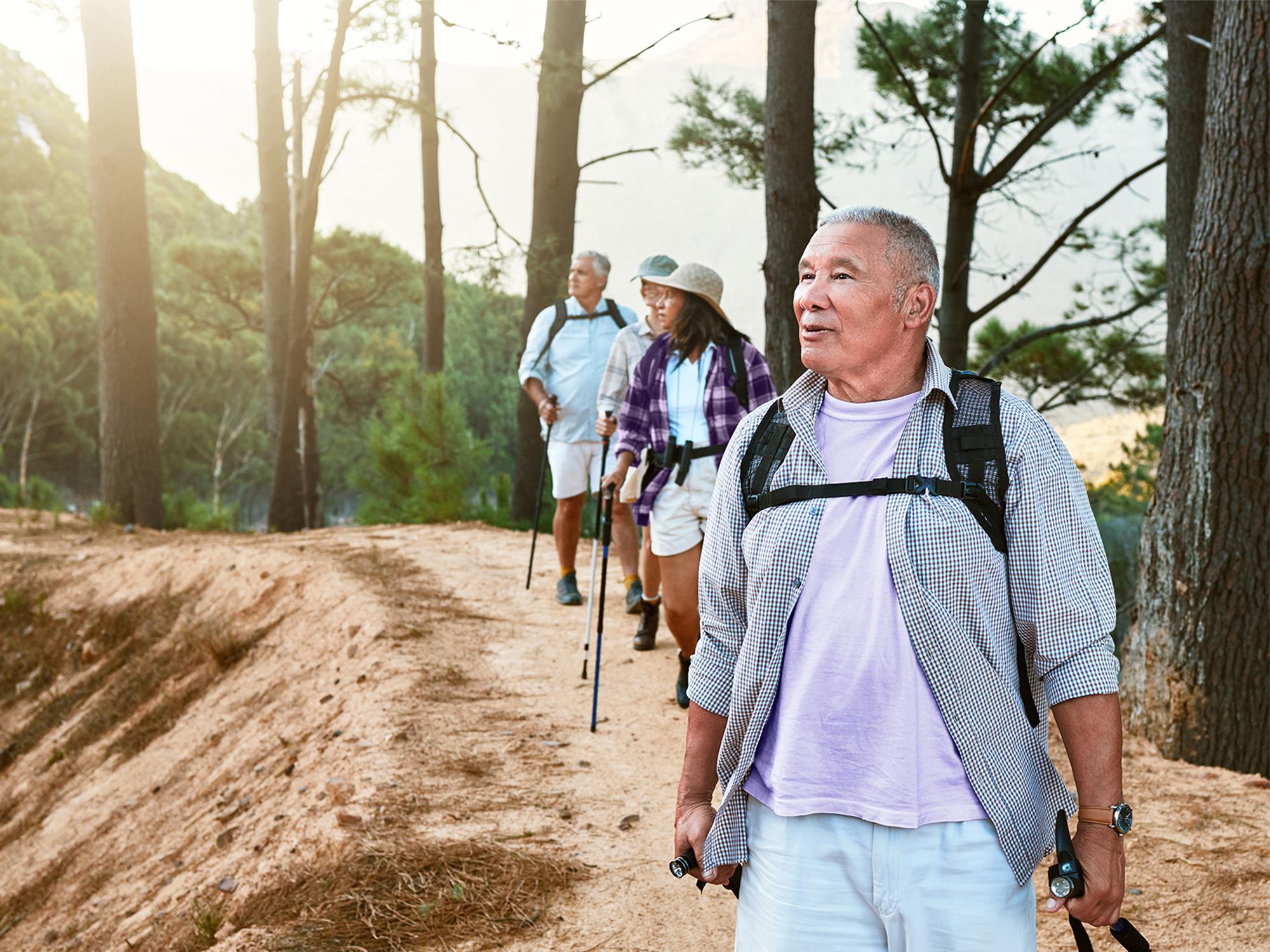Group of friends hiking outdoors, using hearing aids for better communication.