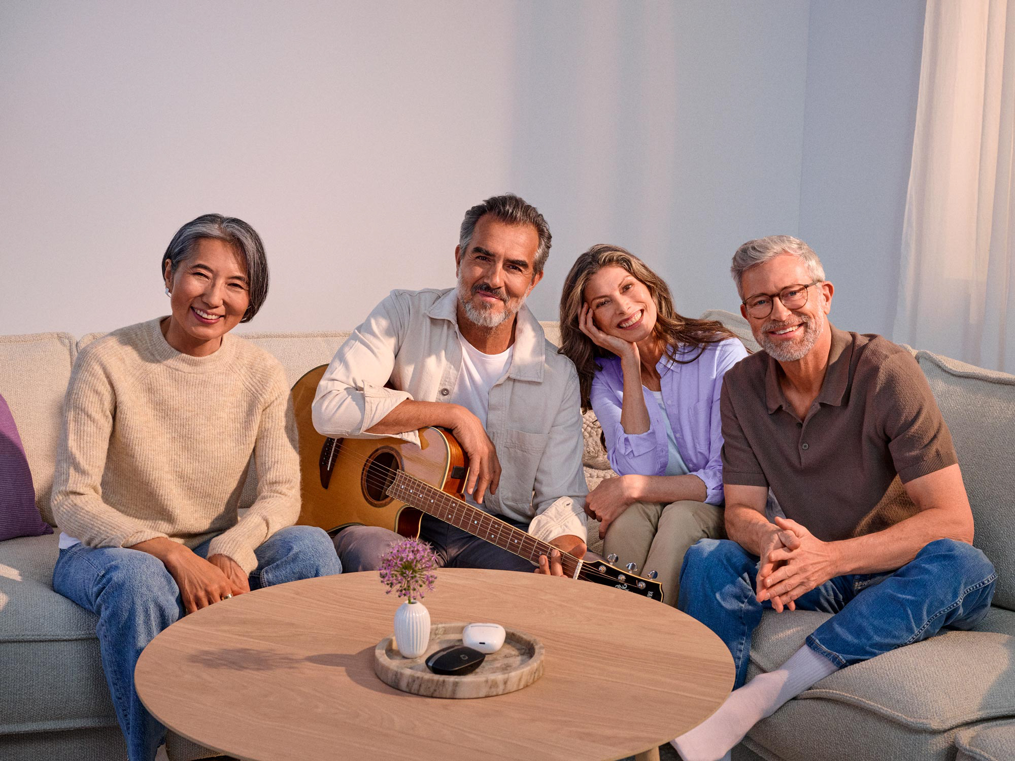 Friends gathered around a guitar performance, sharing joy with hearing aids.