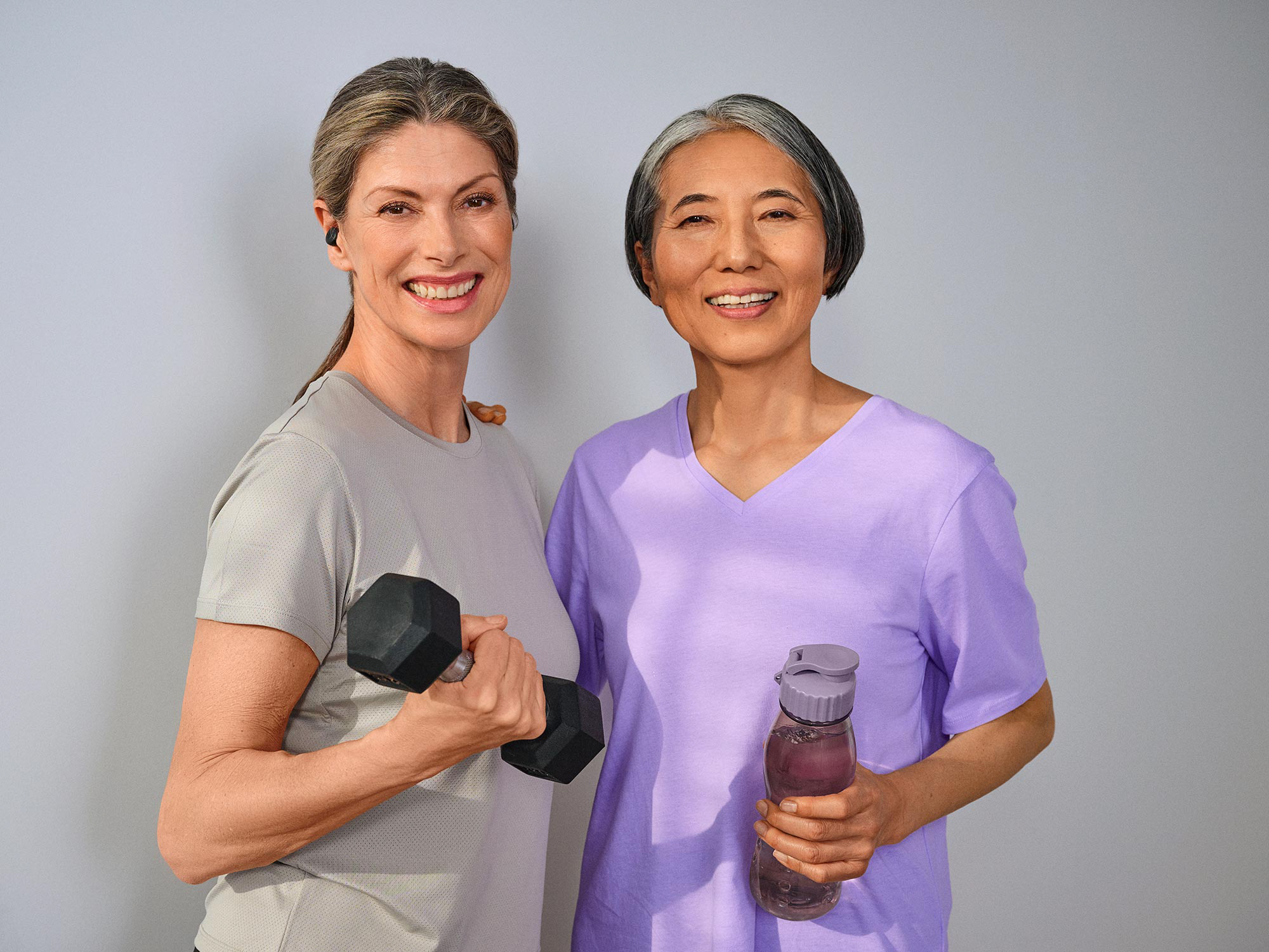 Women friends working out together, wearing hearing aids for clear interactions.