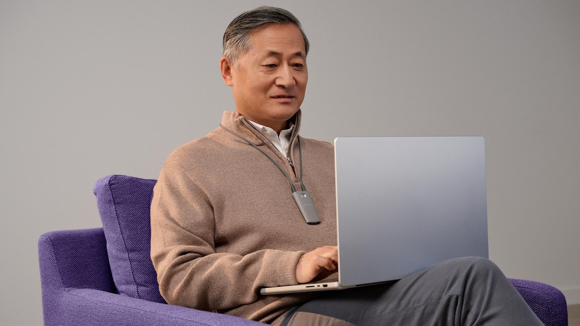 Content man working on a computer, wearing hearing aids.