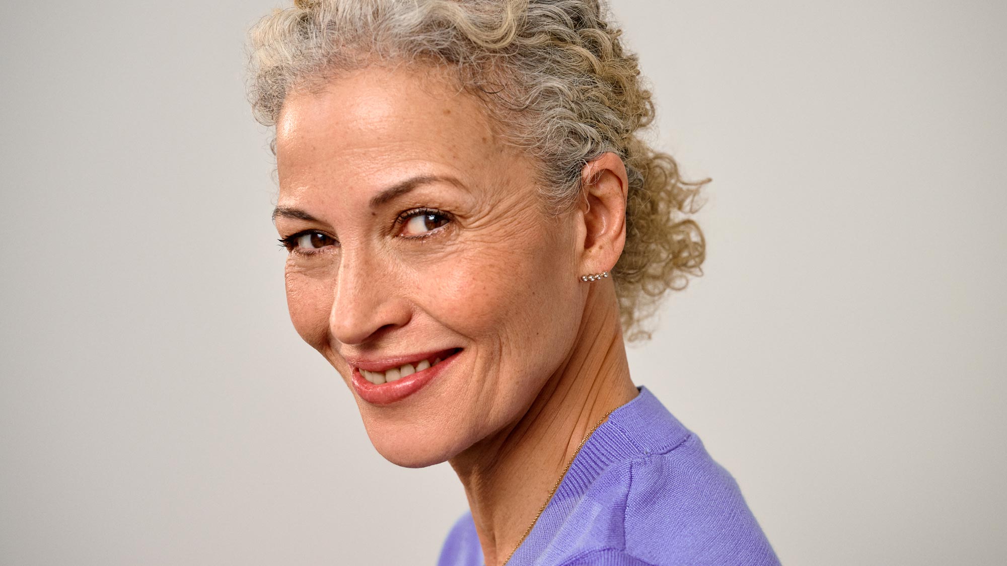 Content woman glancing sideways, showcasing hearing aids.