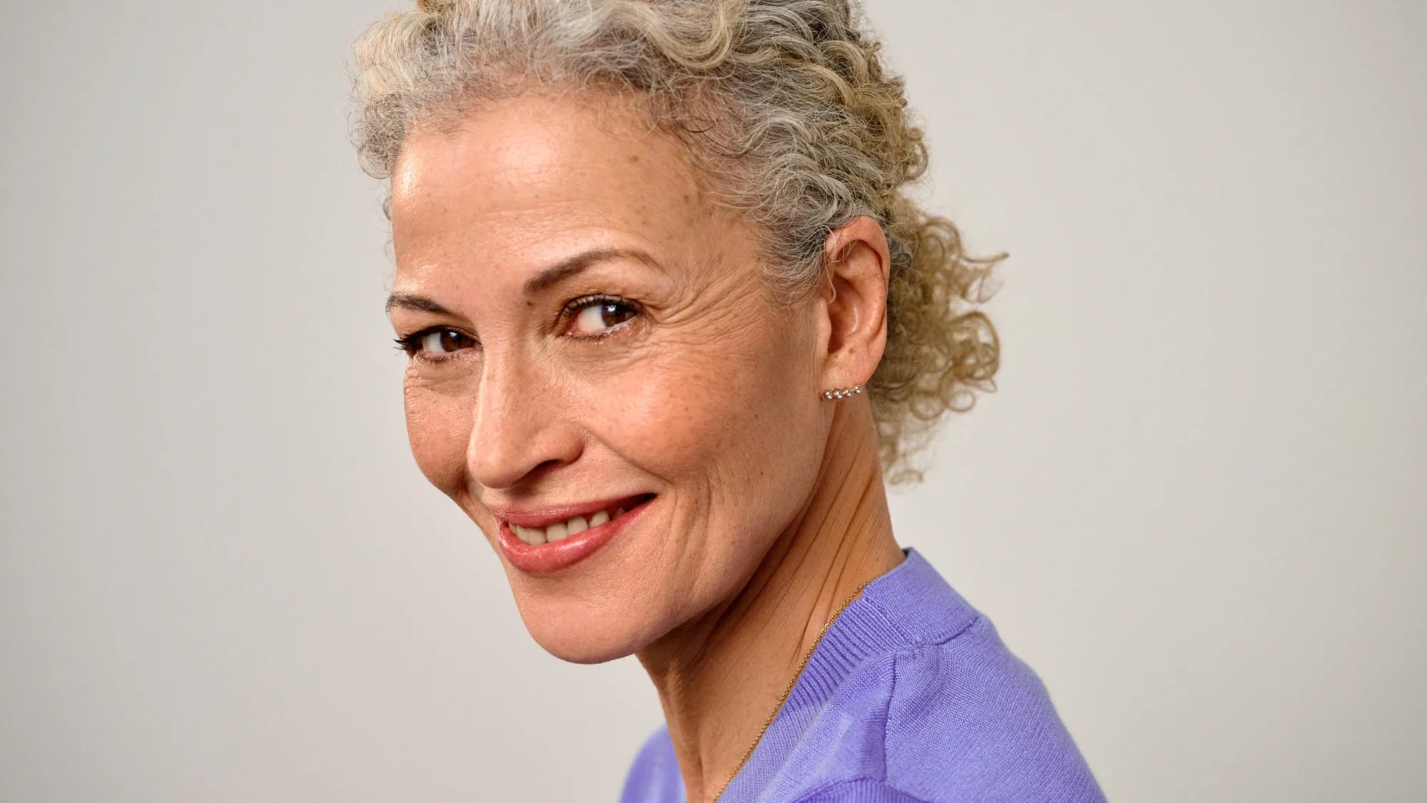 Content woman glancing sideways, showcasing hearing aids.
