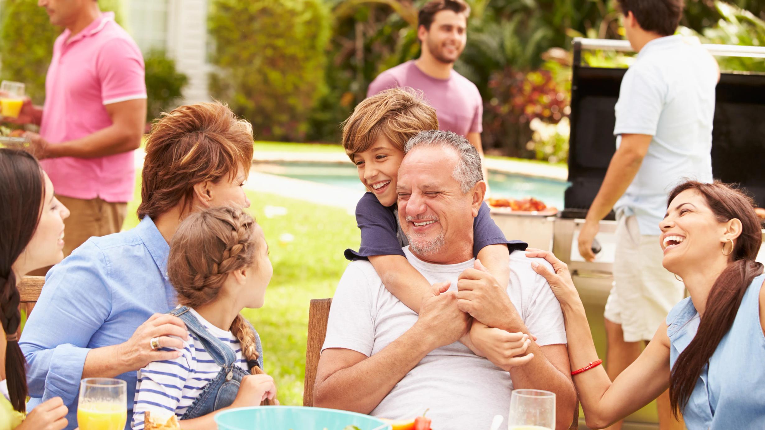 Multi generation family enjoying meal in garden together using hearing aids